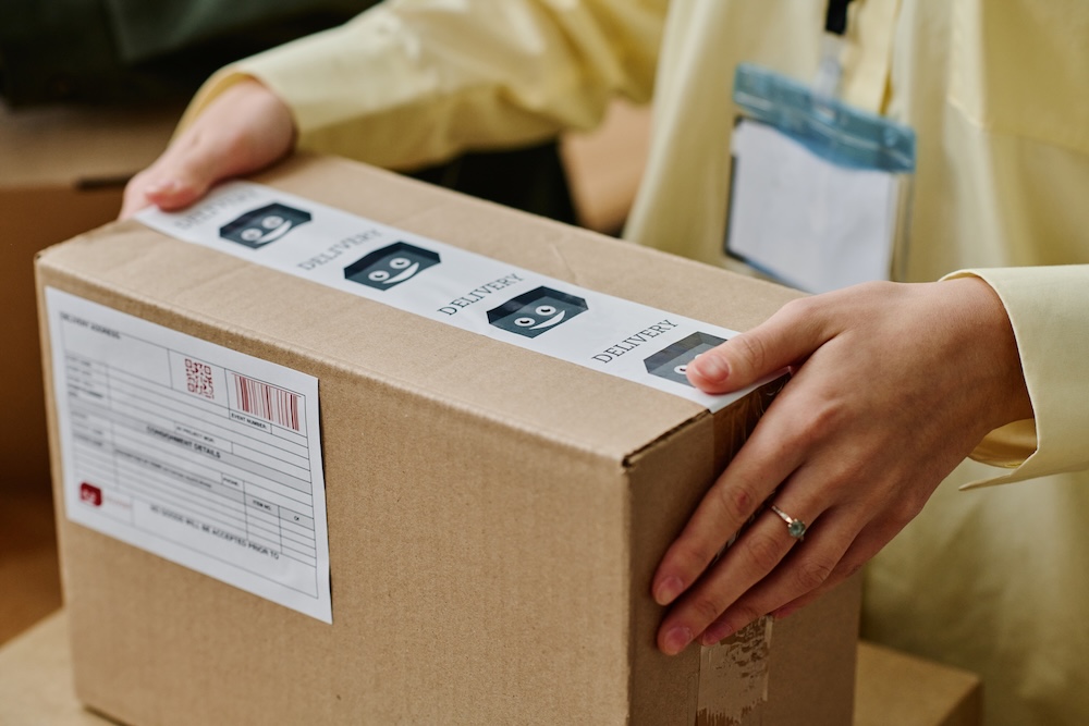 osoba niosąca paczkę do wysyłki 